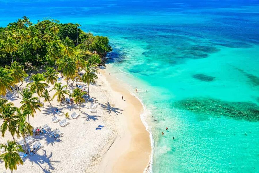 Palms over white sand and shallow turquoise water on the Dominican east coast